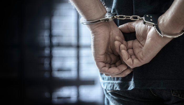 A man in handcuffs holds his hands up