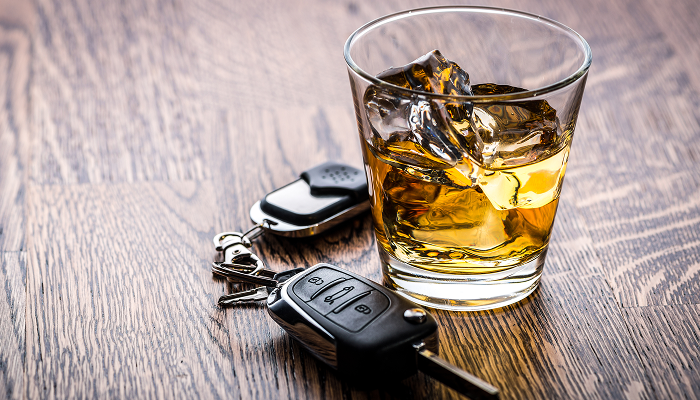A glass of alcohol next to a car key