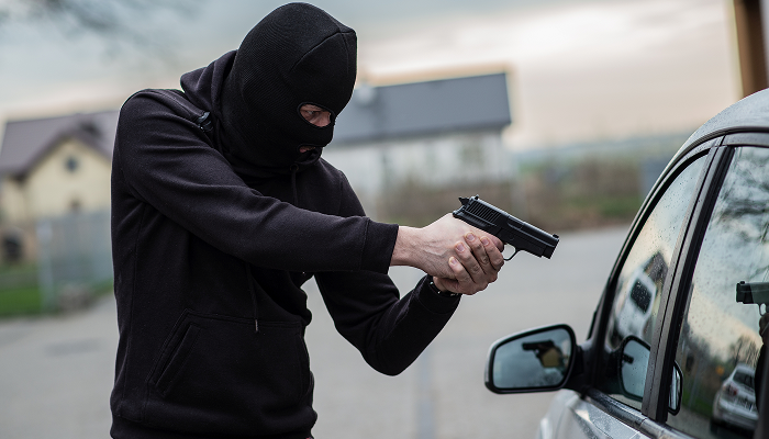 A man in a black hoodie is seen with a gun, implying an act of assault
